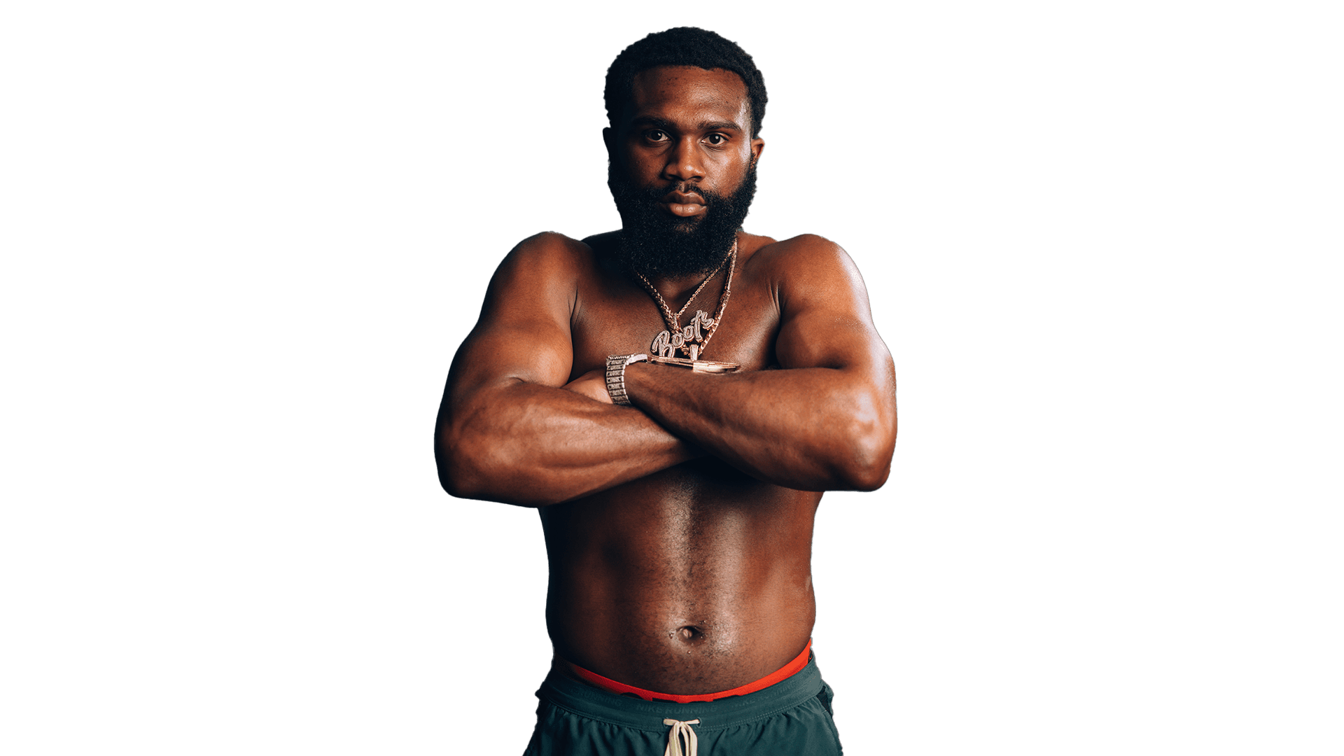 Jaron “Boots” Ennis crosses his arms, wearing chains and staring down the camera.