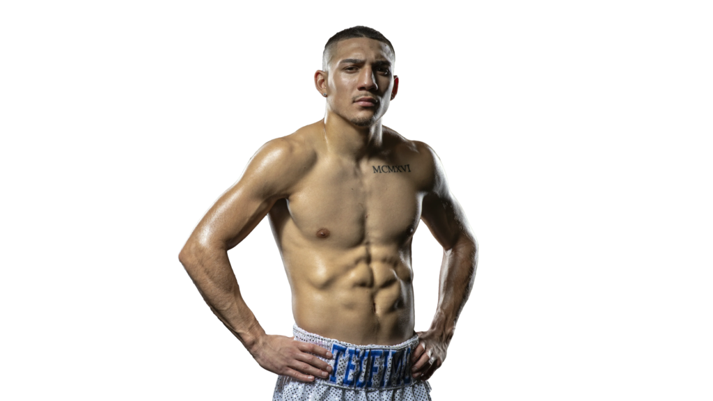 Teofimo Lopez standing shirtless with hands on hips and a focused gaze.