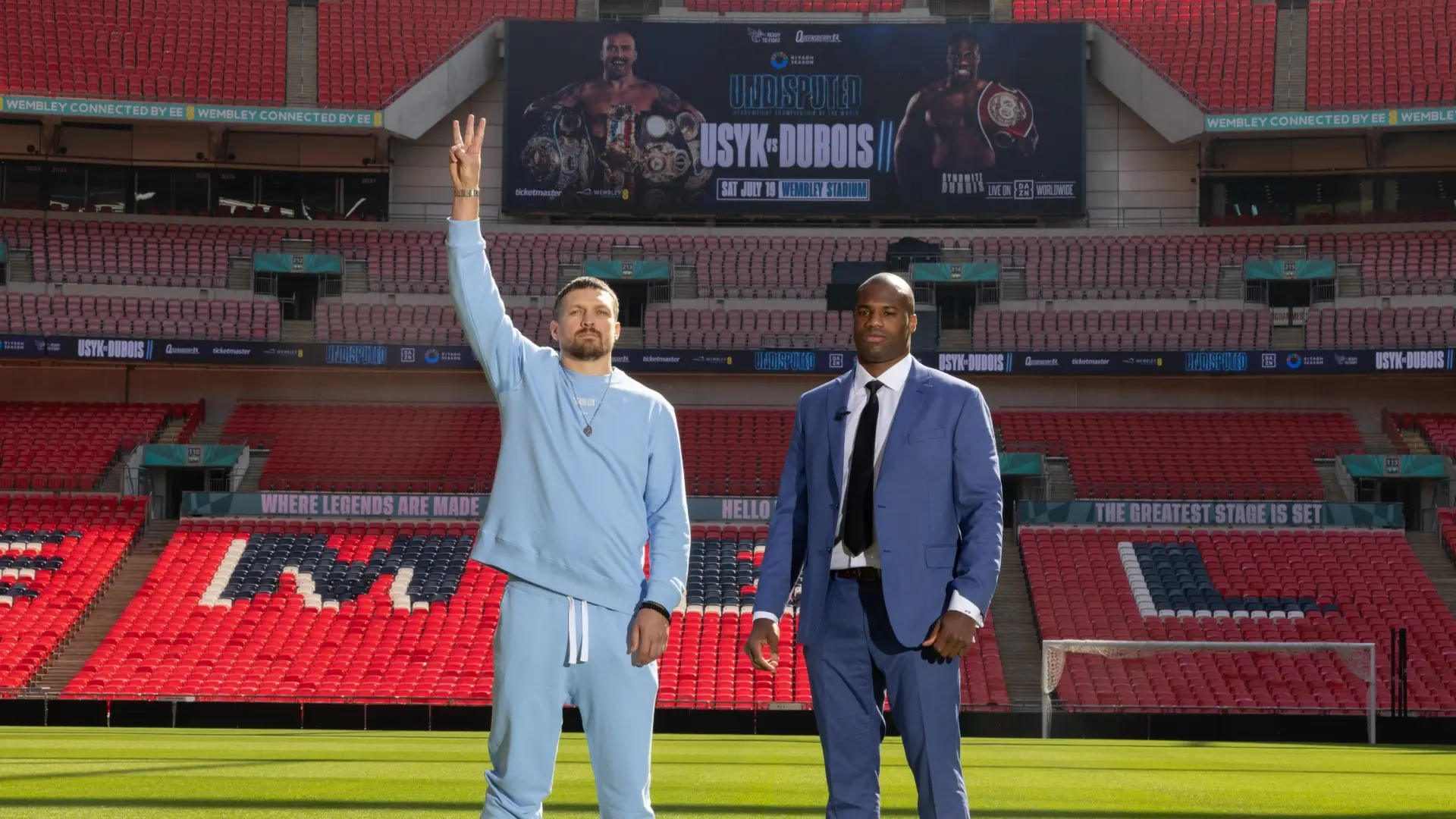 Oleksandr Usyk and Daniel Dubois pose at Wembley Stadium with their rematch banner in the background.