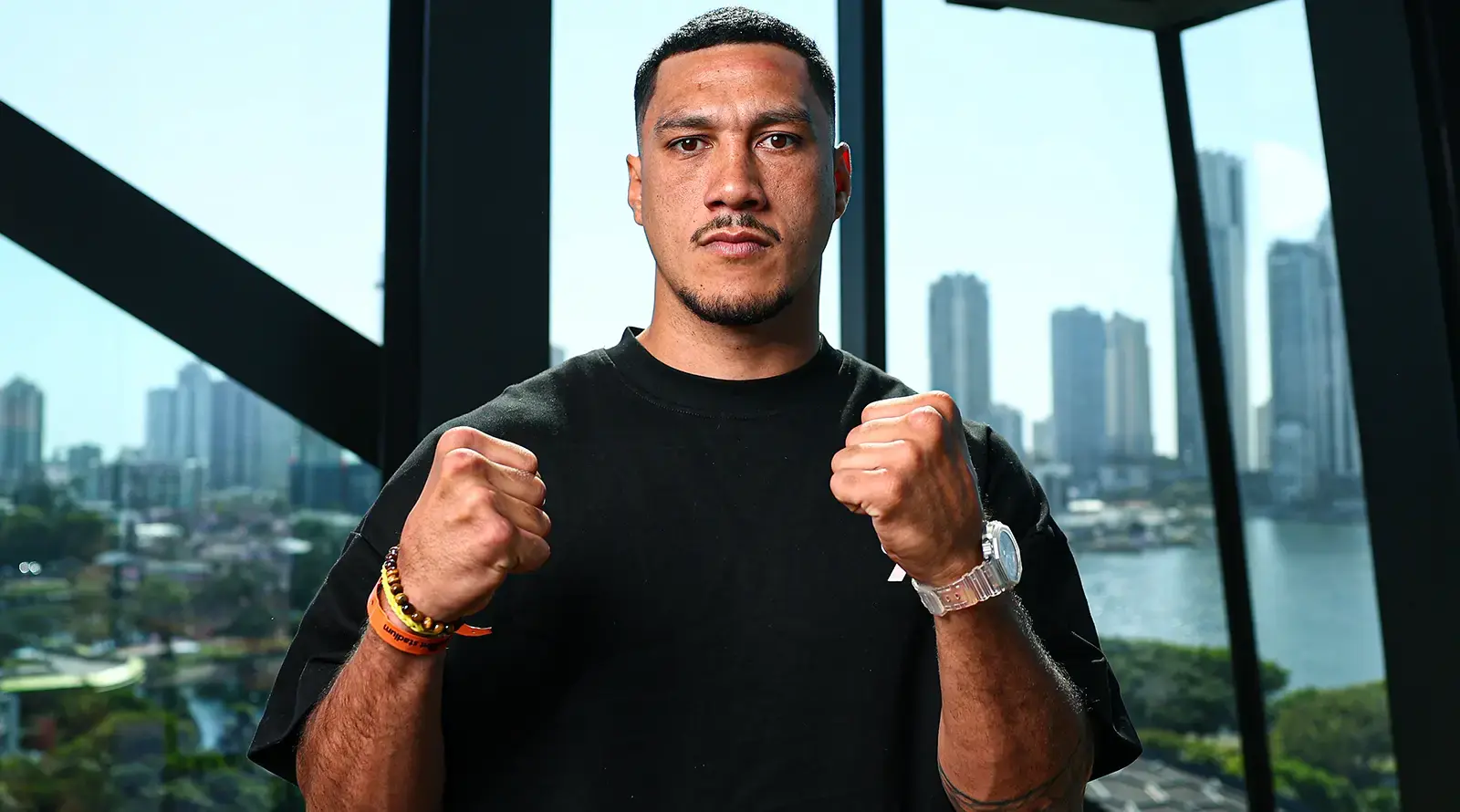 Jai Opetaia poses with fists raised in front of a city skyline.